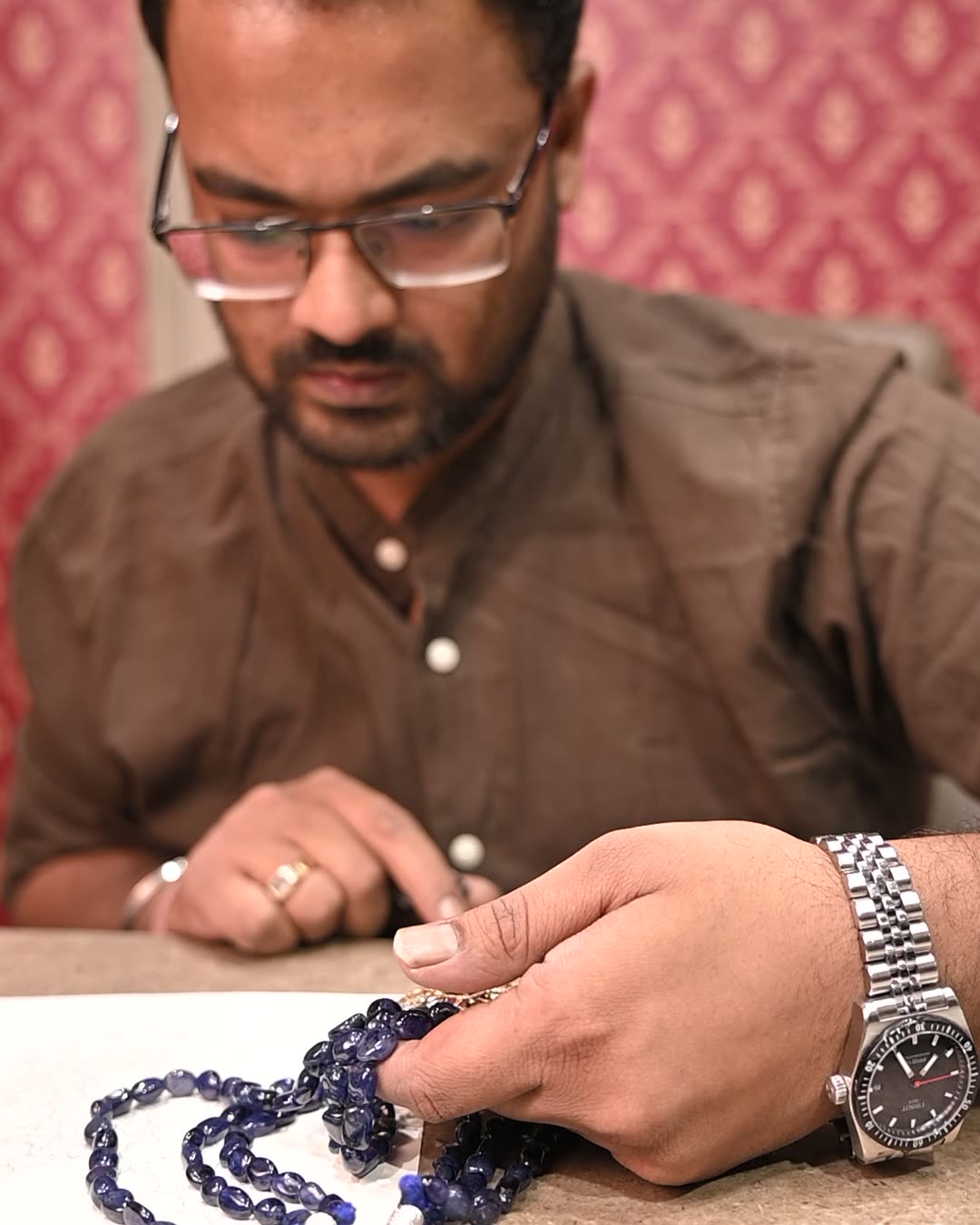 Ripuvanjay looking over a strand of blue stones